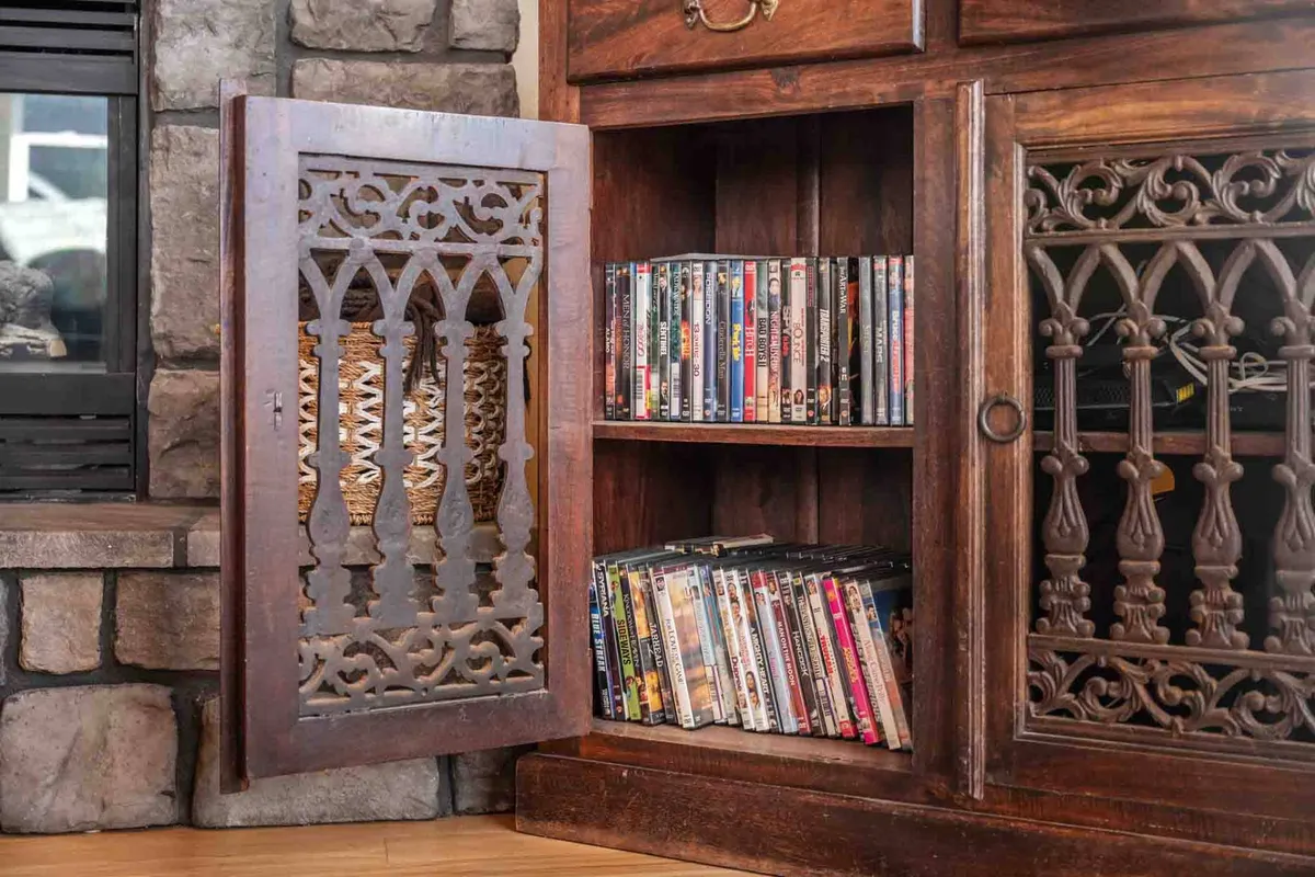 This interior scene features an ornate wooden cabinet displaying a curated collection of DVDs, hinting at the cozy movie nights available. The nostalgic mood and decorative details create a warm, inviting space for family and friends to gather and unwind after a day of exploration.